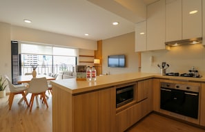 A modern kitchen with wooden cabinets, a built-in oven, and a dining area with a table and chairs. - w* |  Airy 2BR w/ Balcony in Prime Miraflores (Miraflores)