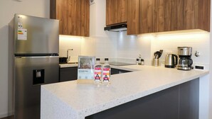 A modern kitchen with wooden cabinets, a stainless steel refrigerator, a coffee maker, and two bottles of a beverage. - w* | Prime 2BR w/ Balcony in Miraflores (Miraflores)