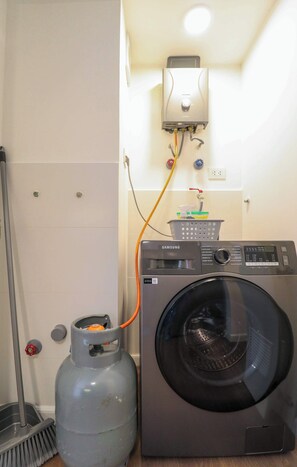 A compact laundry setup with a washing machine and a gas cylinder, connected to a wall-mounted heater. - w* | Prime 2BR w/ Balcony in Miraflores (Miraflores)