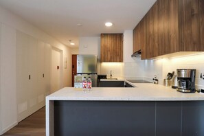 Cocina moderna con una isla central, electrodomésticos de acero inoxidable y muebles de madera.
