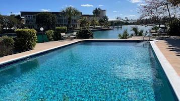 A clear swimming pool with a view of a building and a dock in the background.