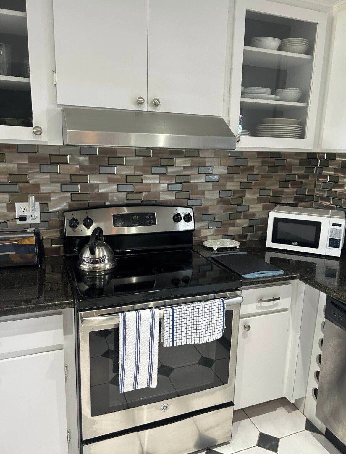 A kitchen with a black stove, a microwave, and white cabinets.