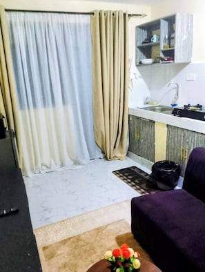 A compact living space with a kitchenette, a sofa, and a small table with a vase of flowers. - Budget studio apartment in charming Rungiri Waiyaki way perfect for relaxing (Rungiri)