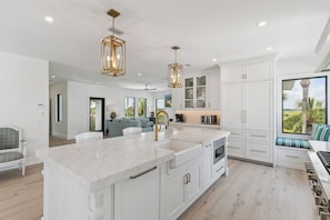 A spacious kitchen with a large island, white cabinetry, and pendant lighting. - Villa Del Mar - East Beach (St Simons Island)