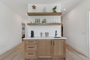 A kitchen with wooden cabinets, a white countertop, and a coffee maker. - Villa Del Mar - East Beach (St Simons Island)