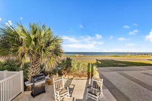Eine Terrasse mit Grill, zwei Stühlen und Meerblick.