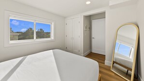 Quarto com cama, janela, guarda-roupa e espelho.