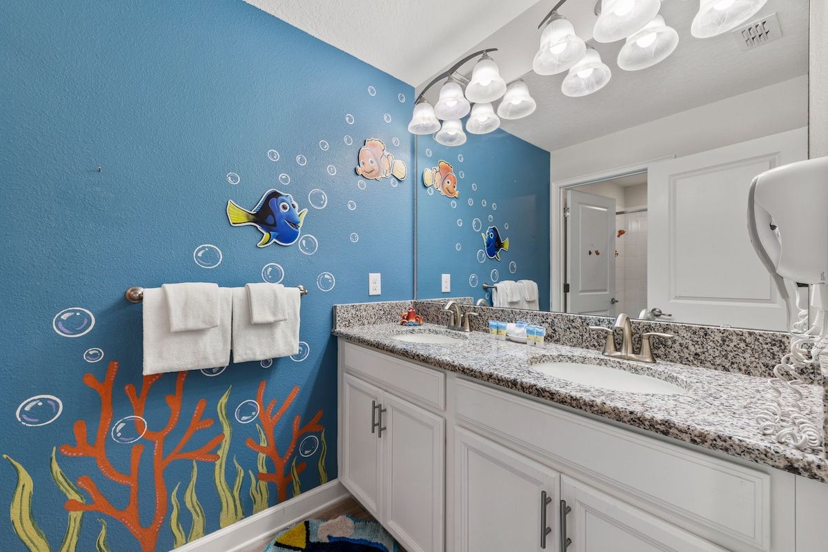 A bathroom with a blue wall, two sinks, white cabinets, and a mirror.