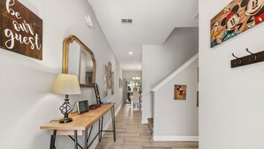 A hallway with a wooden bench, a lamp, and a sign that says 'be our guest.' - Private Pool *Clubhouse Amenities *BBQ Grill (Kissimmee)