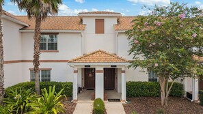 A building with a covered entrance, a palm tree, and a flowering tree. - Private Pool *Clubhouse Amenities *BBQ Grill (Kissimmee)