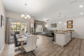 Een ruime woonkamer met een eettafel, zitplaatsen en een keukeneiland.
