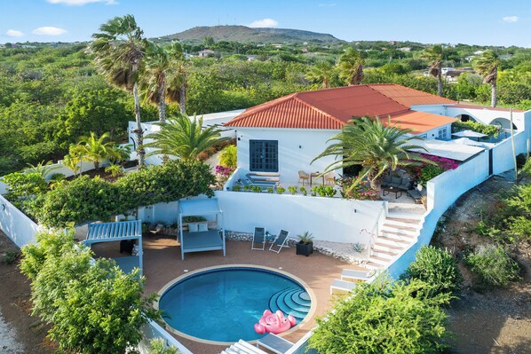 A house with a swimming pool, outdoor seating, and a view of the surrounding greenery. - Grand View: The Room with a Spectacular View (Willemstad)