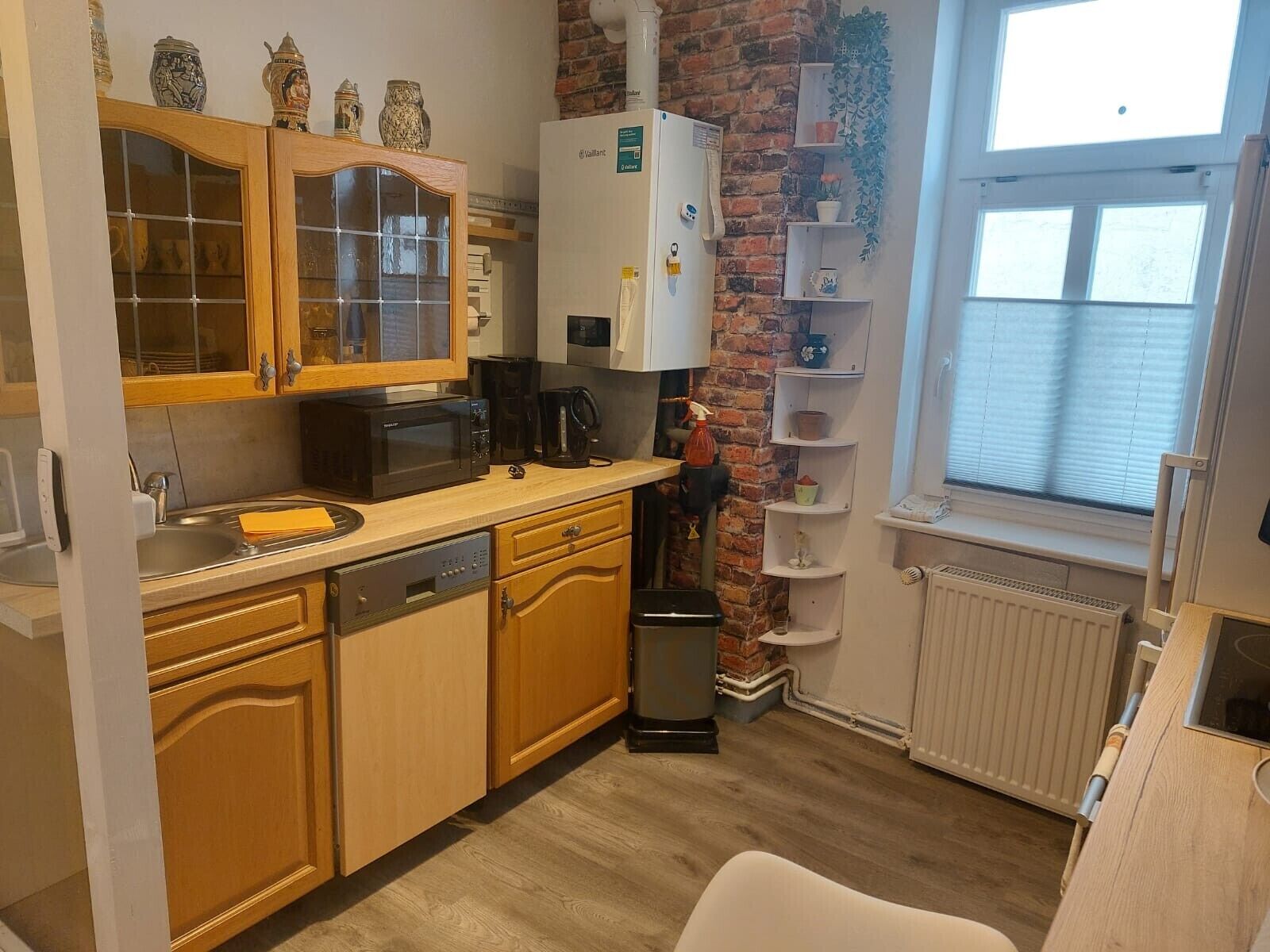 Une cuisine compacte avec des meubles en bois, un four à micro-ondes, une machine à café et un radiateur.