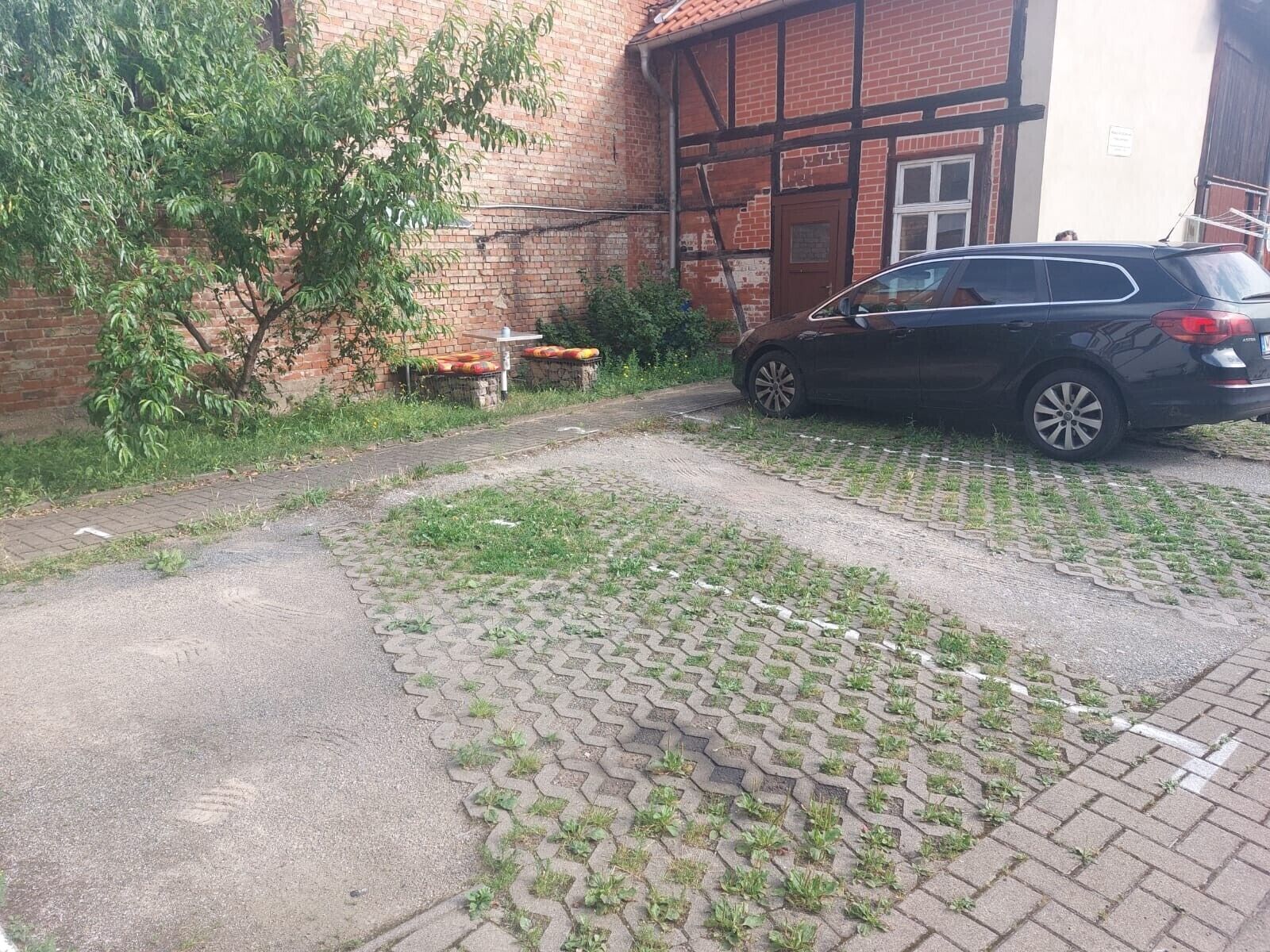 A paved driveway leading to a building with a brick facade and a parked car.