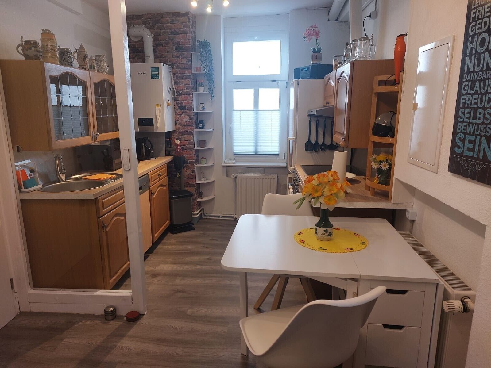 A compact kitchen with a white countertop, wooden cabinets, and a brick wall.