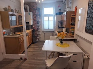A compact kitchen with a white countertop, wooden cabinets, and a brick wall. - Apartment 'Ferienwohnung An der Kuhgasse' with Shared Garden and Wi-Fi (Wernigerode)