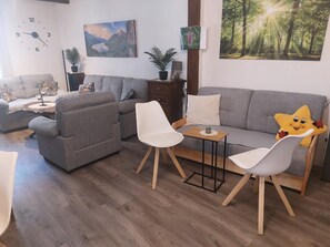 A living room with a grey sofa, two white chairs, a small table, and a star-shaped cushion. - Apartment 'Ferienwohnung An der Kuhgasse' with Shared Garden and Wi-Fi (Wernigerode)