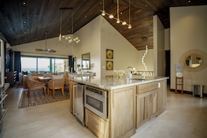 A modern kitchen with a large island, wooden cabinets, and stainless steel appliances.