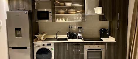 A compact kitchen with a built-in washer, oven, microwave, and a small sink.