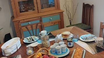 Een eettafel gedekt met borden, glazen en een mand met fruit.