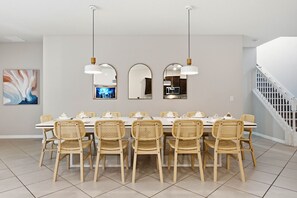 Ein Esszimmer mit einem langen Tisch, sechs Korbstühlen und drei Pendelleuchten.