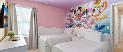 Un dormitorio con dos camas individuales, un televisor de pantalla plana, un mural decorativo y una ventana con cortinas.