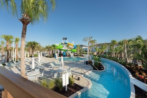 A resort pool area with a water slide, lounge chairs, and palm trees. - Spacious Family Escape, Pool & Game Room (Four Corners)