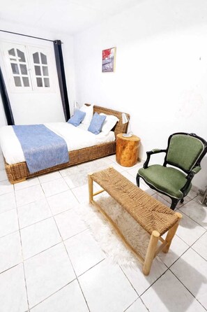 A room with a bed, a bench, a chair, and a small round table.