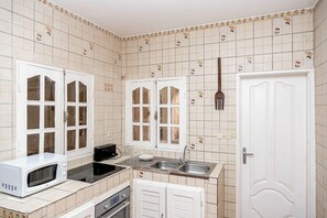 A kitchen with white cabinets, a microwave, a stove, and a sink.