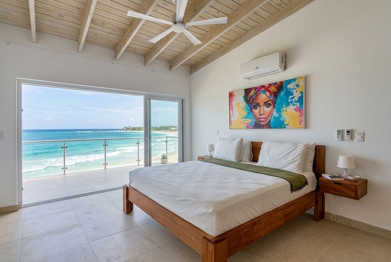 A bedroom with a large bed, a view of the ocean, and a ceiling fan.