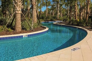 A curved swimming pool with a 3 FT depth marker, surrounded by palm trees and a tiled walkway. - Davenport 5BR Pool & Game Room by AllevoHomes (Davenport)