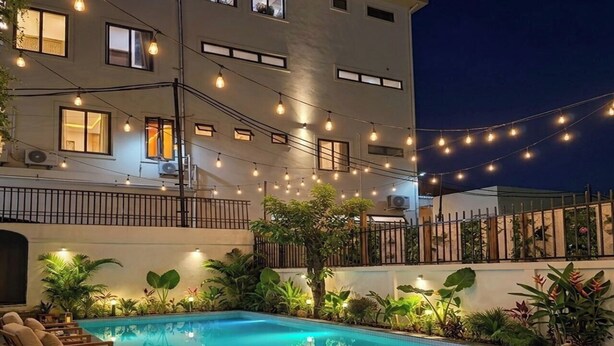 An outdoor swimming pool with lounge chairs and string lights.