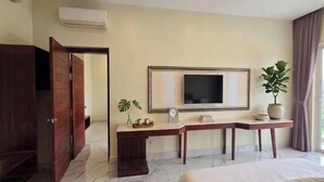 A hotel room with a bed, a TV mounted on the wall, a desk with a plant, and a wardrobe. - Ocean SHV Hotel (Sihanoukville)