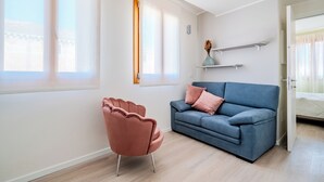 Ett modernt vardagsrum med en blå soffa, en rosa fåtölj och ett trägolv.