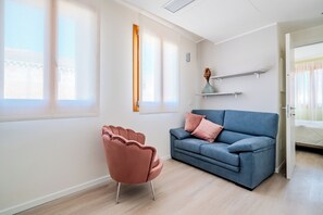 A modern living room with a blue sofa, a pink chair, and a wooden floor. - Monet Suite, 100 meters from the Biennale - Canal View (Venezia)