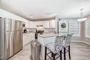 A modern kitchen with stainless steel appliances, a central island, and a washing machine.