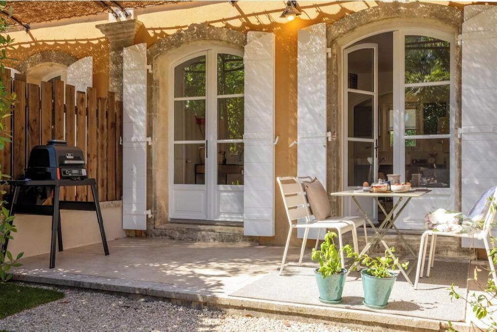 A patio area with a table and chairs, a grill, and potted plants.