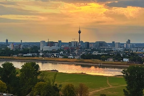 Eine Stadtansicht mit einem markanten Turm und einem Fluss im Vordergrund.