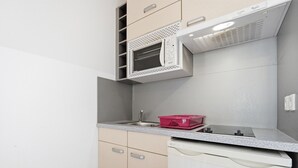 Una cuina compacta amb microones, un rentapeus i un escorredís.