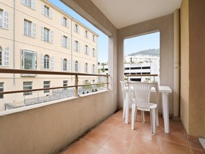 Ein Balkon mit Tisch und Stühlen, mit Blick auf eine Stadtlandschaft mit Gebäuden.