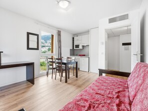A compact living space with a dining area, kitchenette, and a bed with a patterned bedspread. - Apartment with balcony and swimming pool (Grasse)