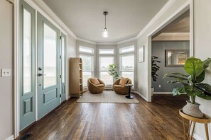Ein geräumiger Flur mit Holzdielenboden, einem großen Fenster und einer Tür mit satinierten Glasfeldern.