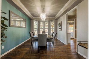 A dining area with a large table, chairs, and a chandelier. - Bentonville Belle • Bike Storage & Trails (Bentonville)