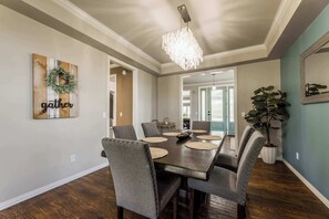 Una sala da pranzo con un tavolo in legno, sedie rivestite di grigio e un lampadario.