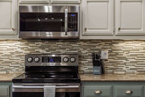 A kitchen with a stainless steel microwave, a Samsung oven, and a tiled backsplash. - Bentonville Belle • Bike Storage & Trails (Bentonville)