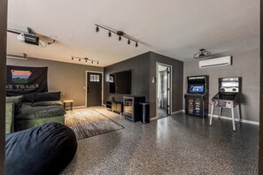 A modern living room with a sofa, a flat-screen TV, a gaming console, and a projector. - Double Black Diamond | Trails | Bike Out | 2 Decks (Bentonville)