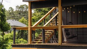 Eine Holzterrasse mit einer Treppe zu einem überdachten Bereich, umgeben von einem Metallzaun.