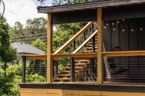 A wooden deck with a staircase leading to a covered area, surrounded by a metal fence. - Double Black Diamond | Trails | Bike Out | 2 Decks (Bentonville)