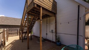 Um deck de madeira com escadas que levam a uma área coberta, um vaso de planta e uma cadeira.