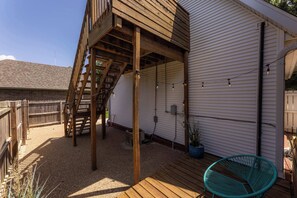 Eine Holzterrasse mit einer Treppe zu einem überdachten Bereich, einem Blumentopf und einem Stuhl.